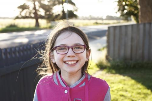 Girl smiling in the late afternoon sun in front yard of home