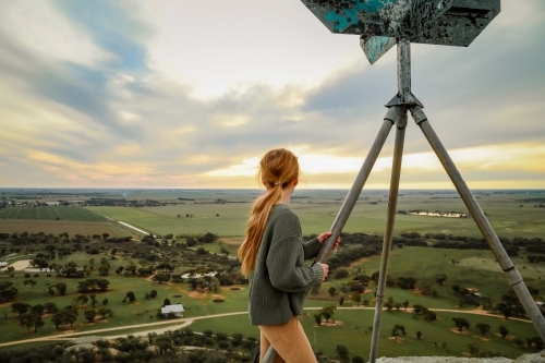 Girl standing at the summit of Pyramid Hill, Victoria looking at view of farmland below - Australian Stock Image
