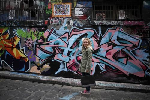 Girl standing in the street in front of graffiti with shopping
