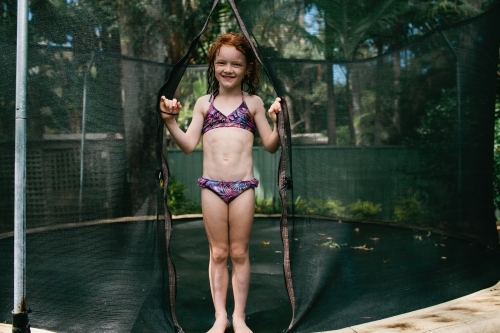 Girl standing on a trampoline in a bikini - Australian Stock Image
