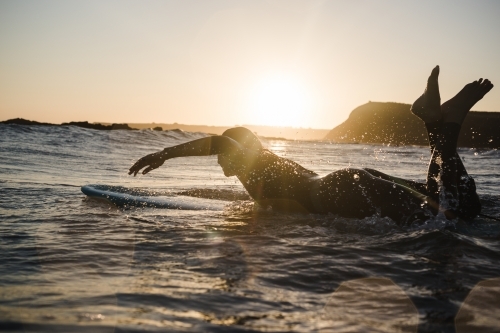 Girl surfing in the ocean on a longboard during sunset