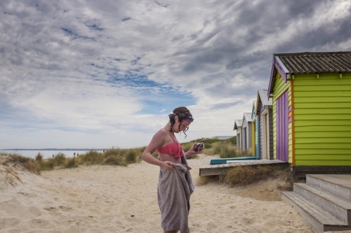 Girl swimming at beach with colourful beach boxes