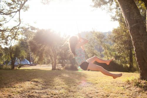 Girl swinging on a rope swing at a campsite - Australian Stock Image