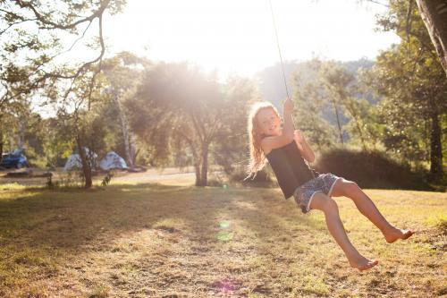 Girl swinging on a rope swing at a campsite - Australian Stock Image