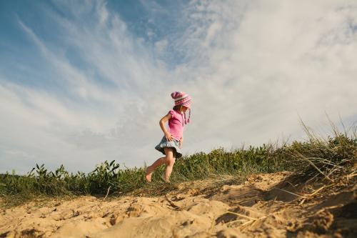 Girl walking along the sand at the beach - Australian Stock Image