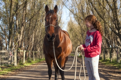 Girl walking her horse in scenic background