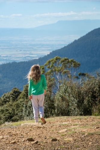Girl walking on mountain overlooking mountains - Australian Stock Image