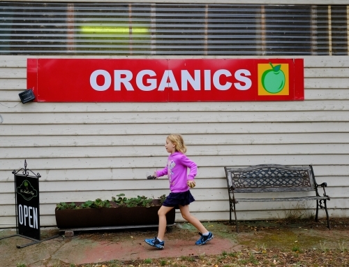 Girl walking past organic fruit farm shop