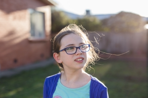 Girl wearing glasses standing in afternoon sun - Australian Stock Image