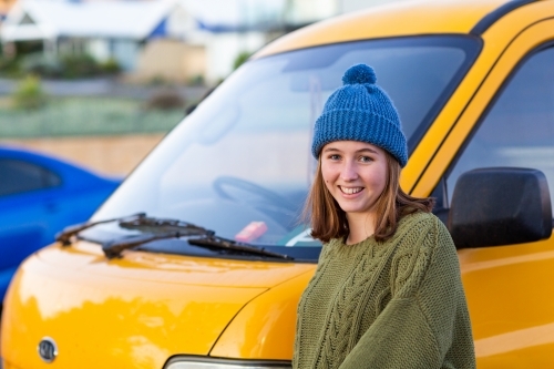 girl wearing knitted beanie in front of yellow van - Australian Stock Image