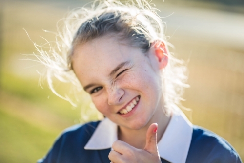 Girl winking and smiling with thumbs up - Australian Stock Image