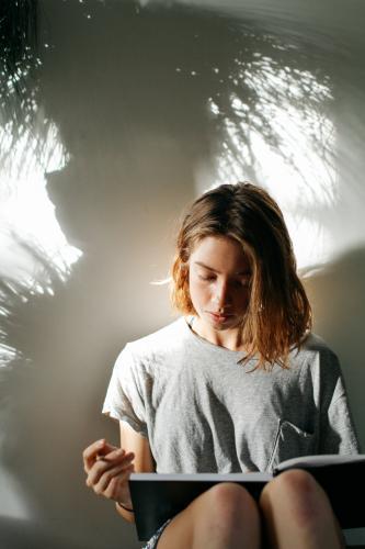 Girl with book and pencil in afternoon light