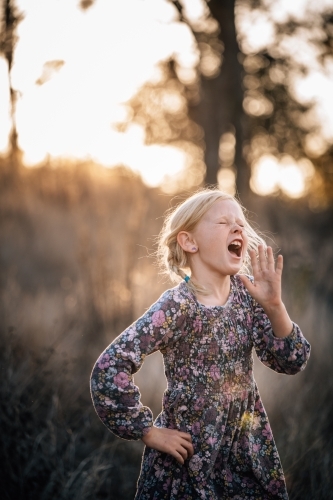 Girl with her hand upto her face singing into the distance - Australian Stock Image