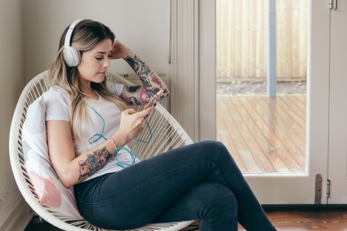 Girl with tattoos creating a playlist on her smart phone