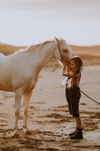 Girl with white horse on the beach at sunset - Australian Stock Image