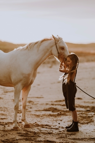 Girl with white horse on the beach at sunset