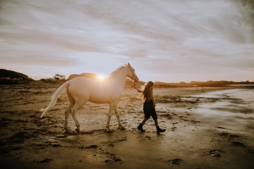 Girl with white horse on the beach at sunset - Australian Stock Image