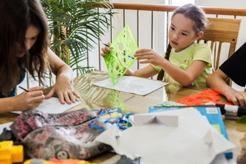 Girls creating artwork, drawing Manga and stencilling at the table - Australian Stock Image
