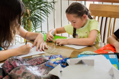 Girls creating artwork, drawing Manga and stencilling at the table - Australian Stock Image