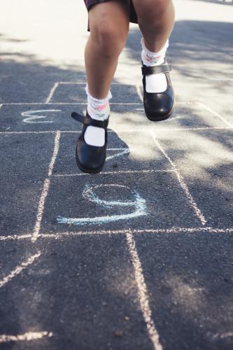 Girls legs jumping on a hopscotch game - Australian Stock Image