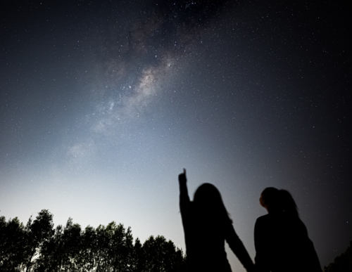 Girls pointing up at the stars in night sky - Astrophotography - Australian Stock Image