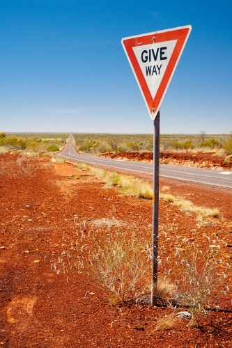 Give way sign in front of a long stretch of highway between Katherine and Tennant Creek,. - Australian Stock Image