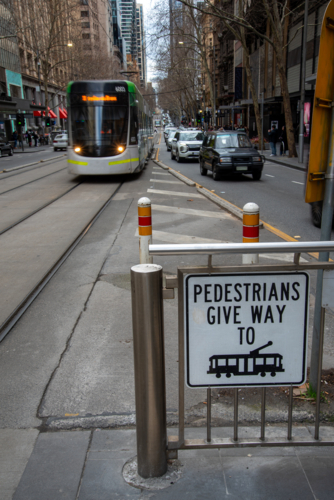 Give way to trams sign with an approaching tram - Australian Stock Image