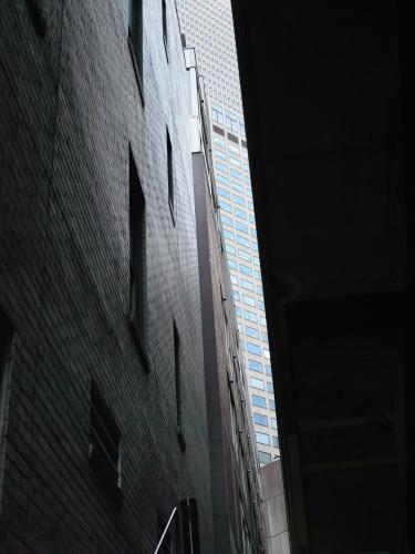Glimpse of modern tower block past old dark laneway building.