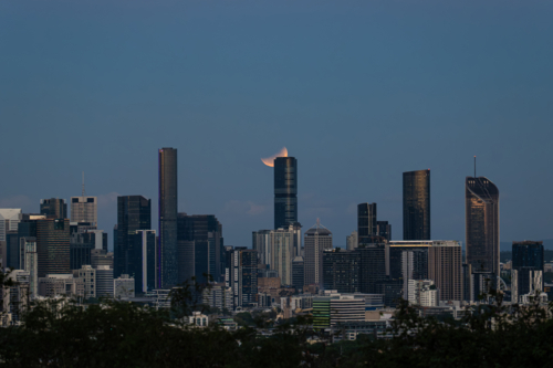 Glowing eclipse of the full moon shining over city skyline - Australian Stock Image