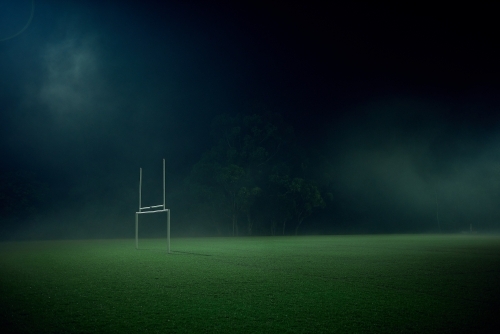 Goal posts on empty sports oval in the fog at night - Australian Stock Image