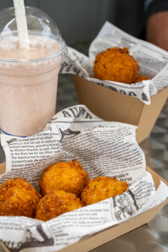 Golden brown croquettes in snack trays lined with faux paper with a cup of milkshake - Australian Stock Image
