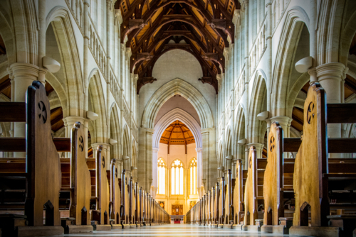 Golden light filling a grand cathedral nave lined with soaring arches. - Australian Stock Image