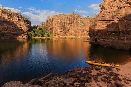 Golden light on pool of water in Nitmiluk Gorge with canoe - Australian Stock Image
