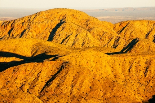 Golden light over the mountains of the Chewings Range in Central Australia. - Australian Stock Image