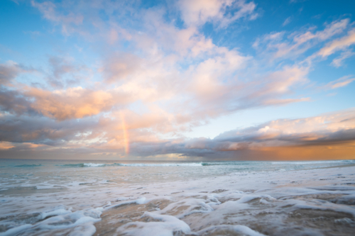 Golden sunset light reflecting on wet beach sand and ocean waves at Scarborough Beach, Perth - Australian Stock Image