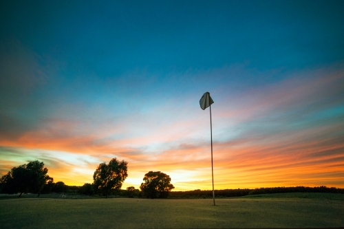 Golf hole flag in front of sunset coloured sky. - Australian Stock Image
