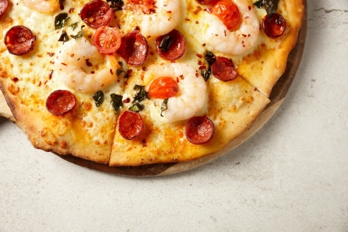 Gourmet wood fired prawn and sausage pizza on table - Australian Stock Image