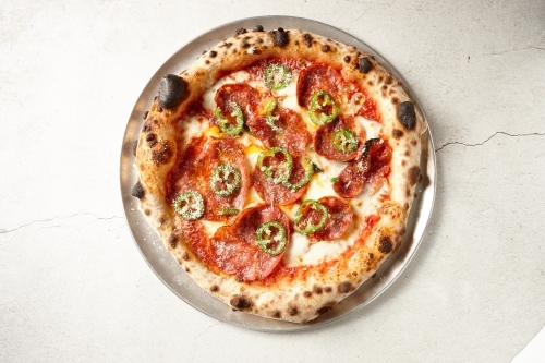 Gourmet wood fired salami pizza on table - Australian Stock Image