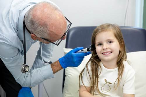 GP doctor doing health check-up for pre-schooler girl at clinic - Australian Stock Image