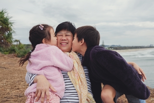 Grandchildren kissing their grandmother