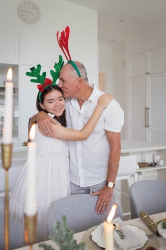 Grandfather and granddaughter standing at Christmas dining table - Australian Stock Image