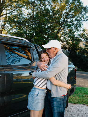 Grandfather embracing granddaughter outside the house. - Australian Stock Image