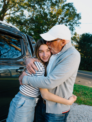 Grandfather embracing granddaughter outside the house. - Australian Stock Image