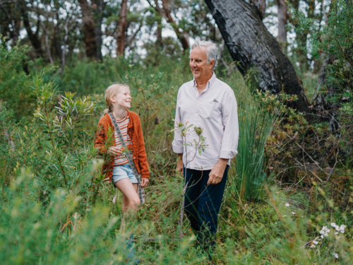 Grandfather exploring Australian Bushland with granddaughter smiling together - Australian Stock Image
