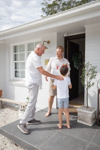 Grandfather, father and son at front door of home with Christmas presents - Australian Stock Image