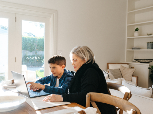 Grandma sitting with her grandson in front of a laptop on the table. - Australian Stock Image