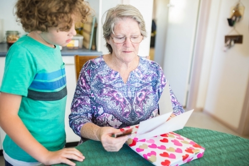 Grandmother opening present reading card with grandchild