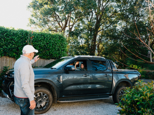 Grandpa waving goodbye to his granddaughter in the car - Australian Stock Image
