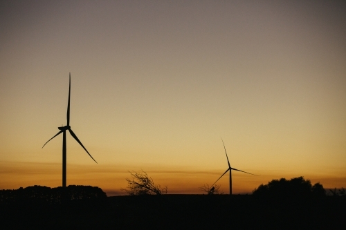 Green energy wind turbine silhouette in the countryside at dusk - Australian Stock Image