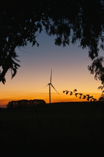 Green energy wind turbine silhouette in the countryside at dusk